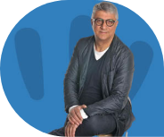 Sitzender Mann mit Brille, blauer Hintergrund.