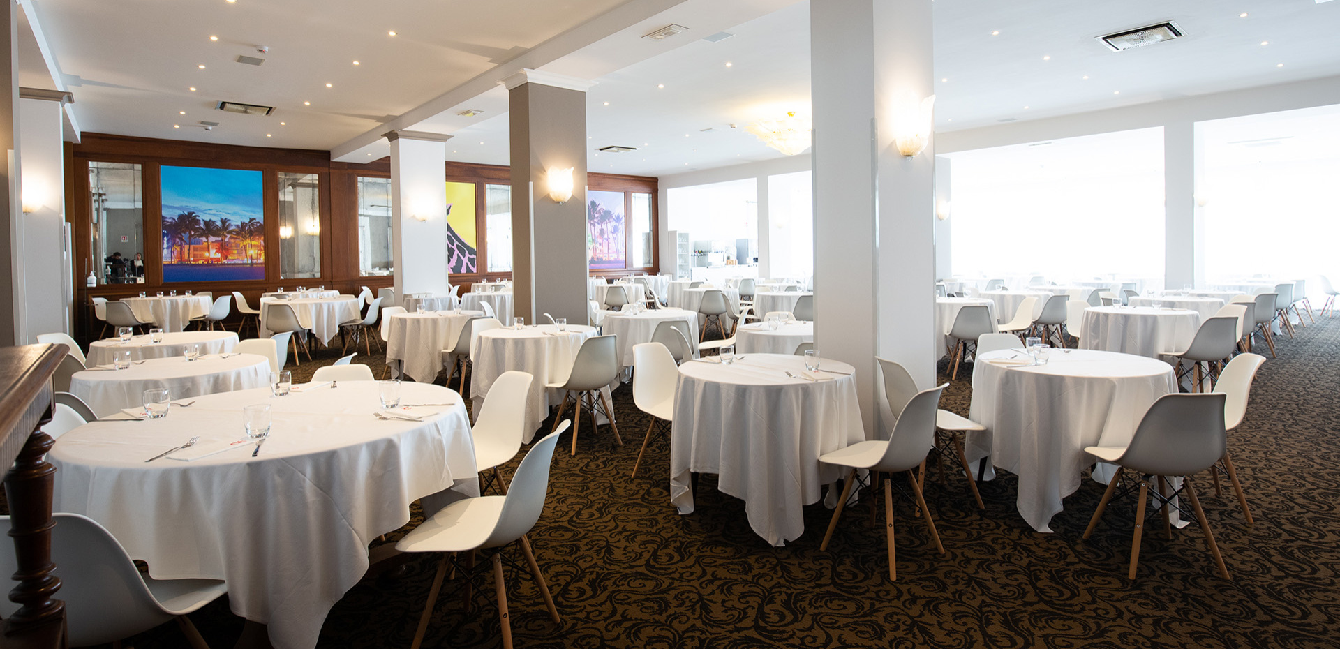 Ristorante luminoso e moderno con tavoli apparecchiati e area buffet.
