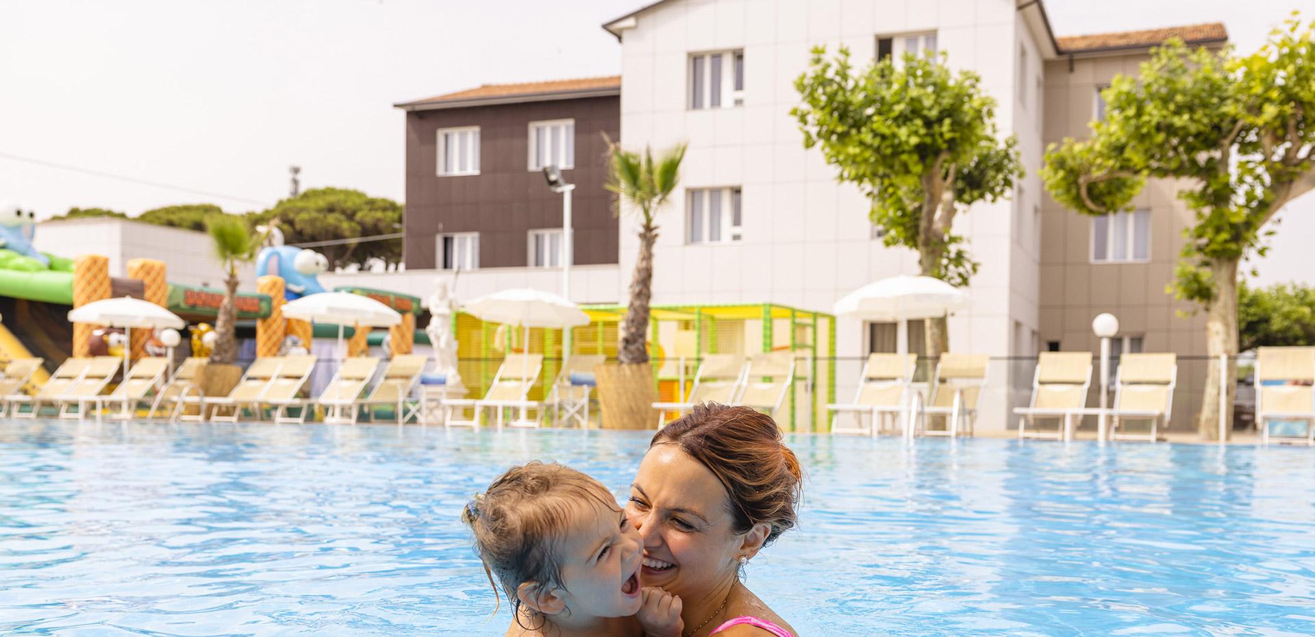 Lächelnde Mutter und Tochter umarmt im Pool, Atmosphäre von Freude und Gelassenheit.