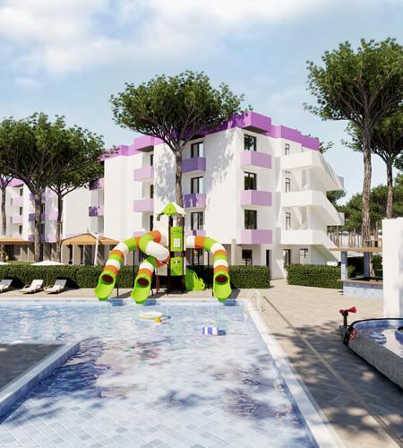 Piscine avec toboggans colorés, bâtiments modernes, arbres luxuriants, ambiance de vacances.