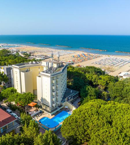 Vue aérienne d'un hôtel avec piscine près de la mer et plage bondée.