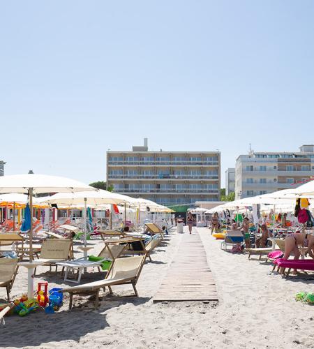 Plage bondée, parasols colorés, soleil éclatant, détente estivale.