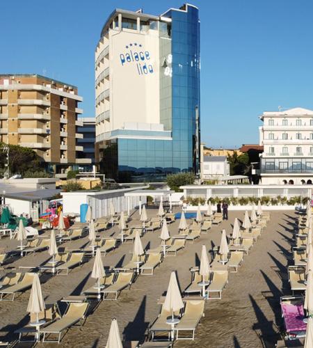 Plage ordonnée, parasols fermés, hôtel moderne, ambiance tranquille et relaxante.