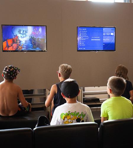 Sala giochi con supereroi, TV e arredi colorati per bambini.