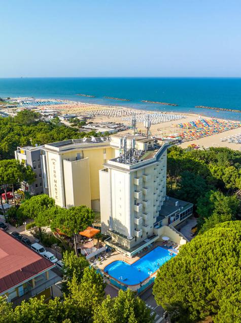 Vue aérienne d'un hôtel avec piscine près de la mer et plage bondée.