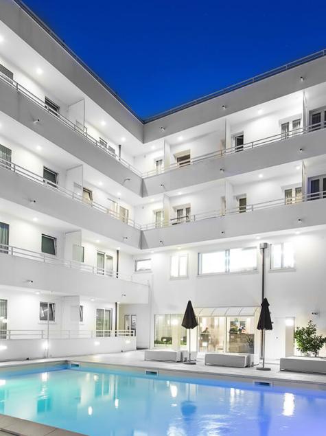 Hôtel moderne avec piscine éclairée la nuit, ambiance relaxante et sophistiquée.