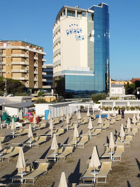 Plage ordonnée, parasols fermés, hôtel moderne, ambiance tranquille et relaxante.