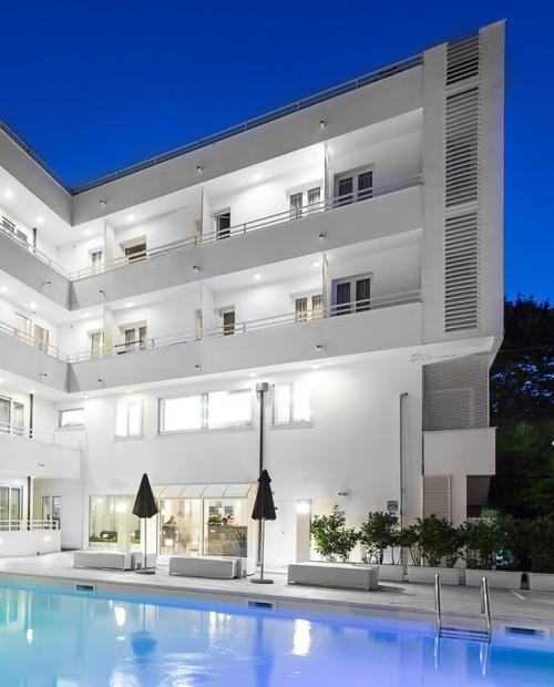 Hotel moderno con piscina illuminata di notte, atmosfera rilassante e sofisticata.