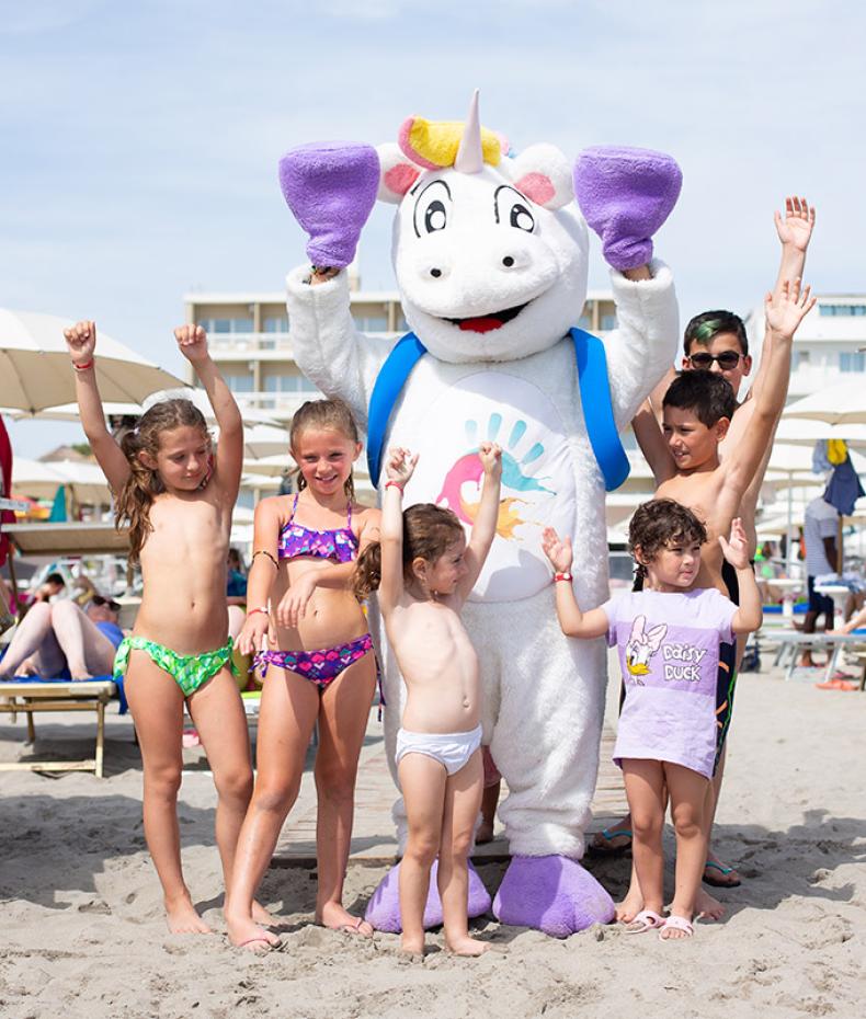 Glückliche Kinder am Strand mit einem Einhorn-Kostüm.